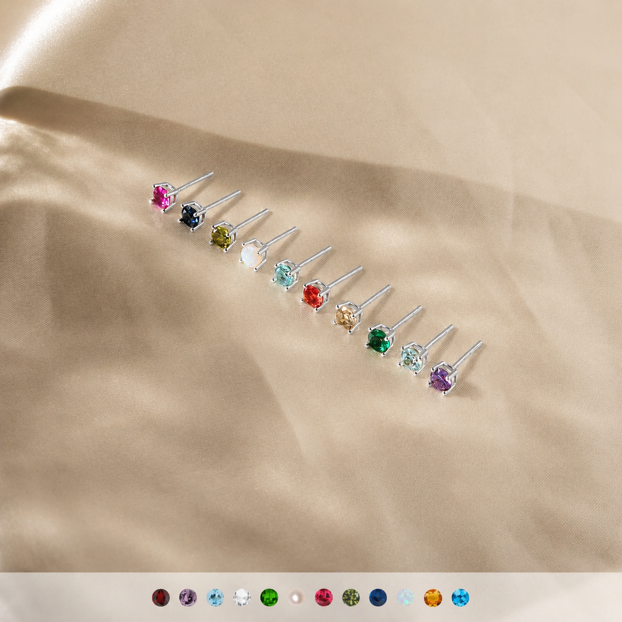 Set of small stud earrings with multicolored gemstones on a beige fabric background