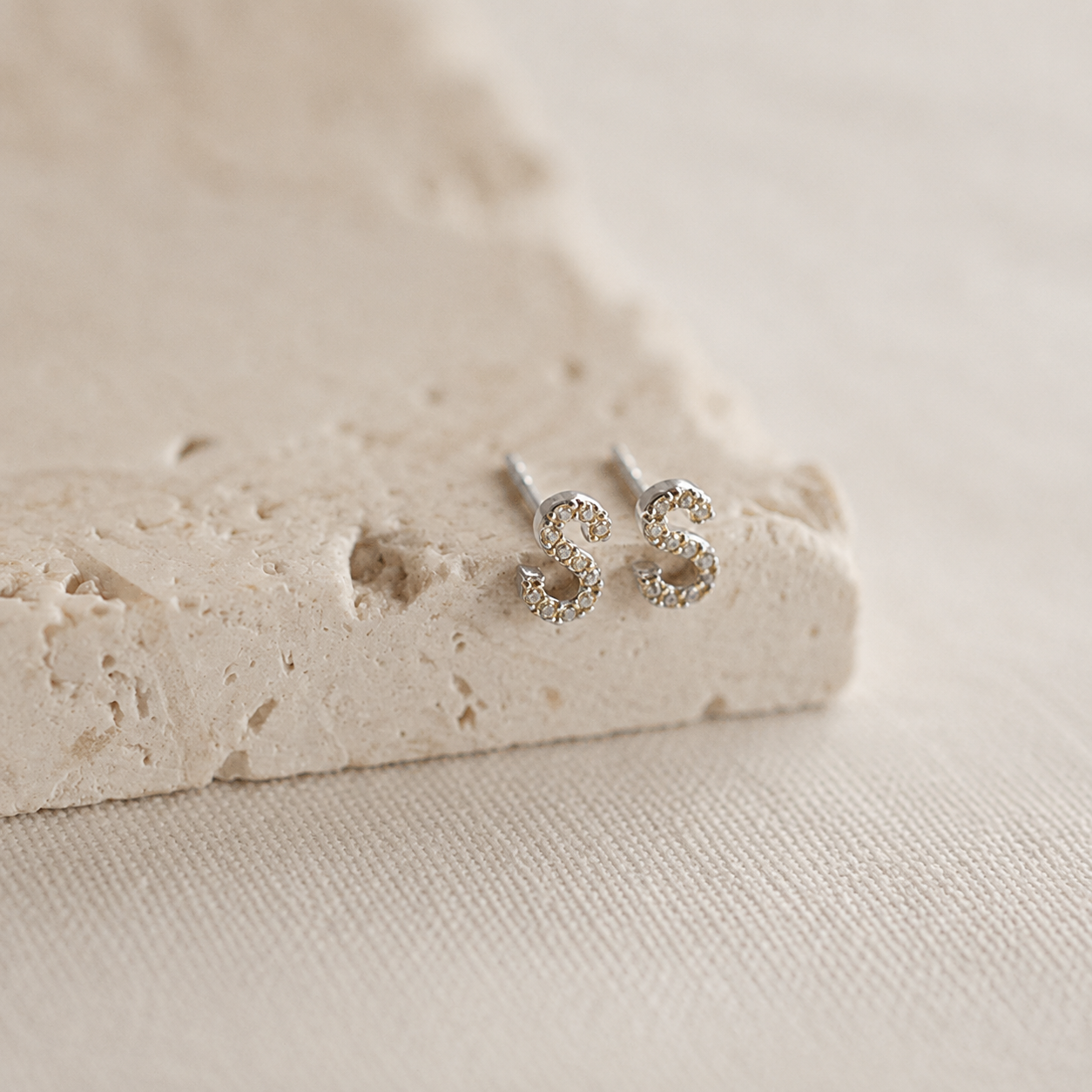 Silver stud earrings on a textured beige surface