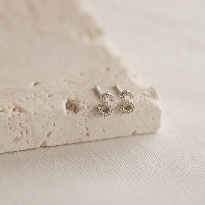 Silver stud earrings on a textured beige surface