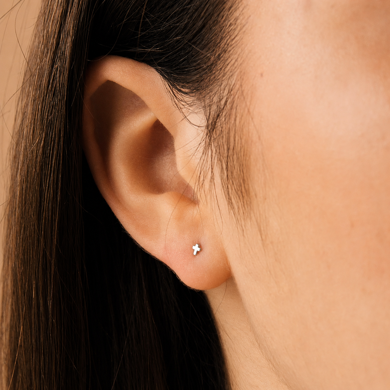 Close-up of an ear wearing a small silver earring with a star design.