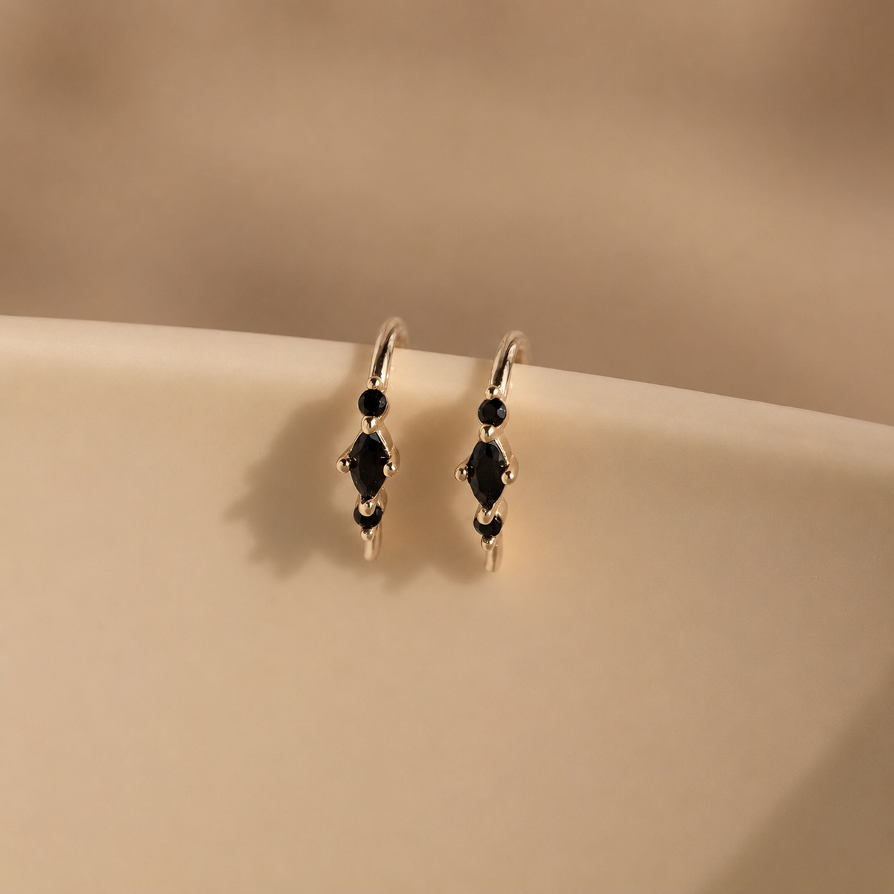 Pair of earrings with black gemstones on a beige surface