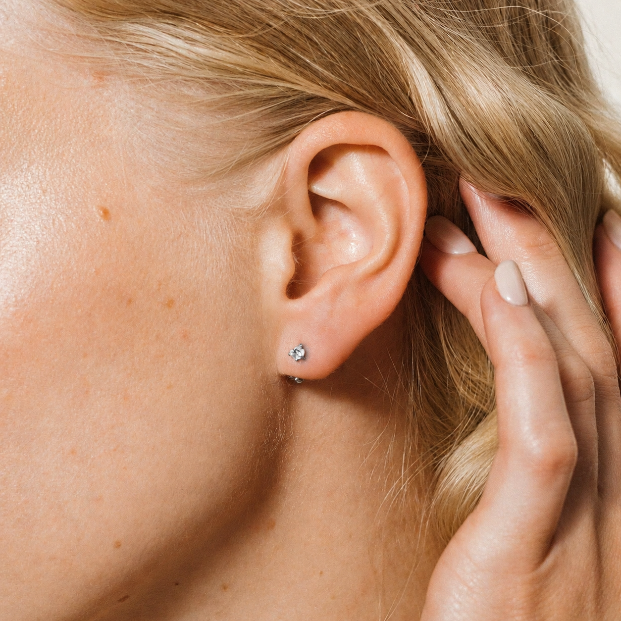 Close-up of a person wearing a small stud earring.