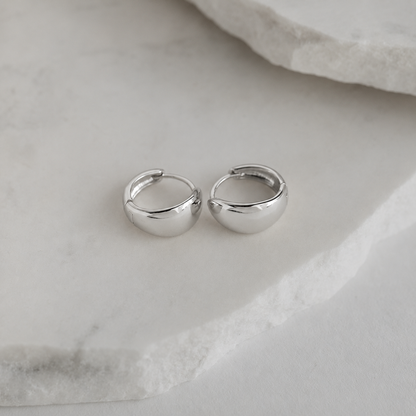 Pair of silver hoop earrings on a marble surface