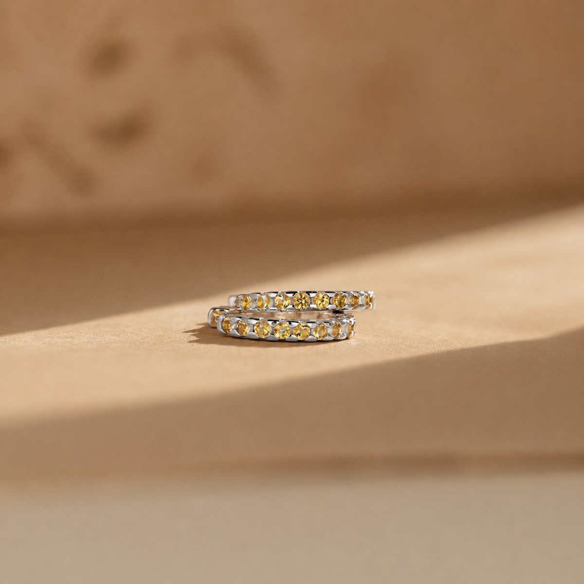 Two gold rings with gemstones on a beige background