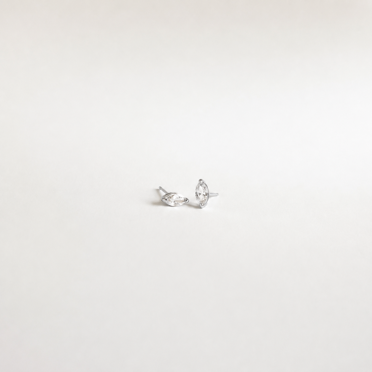 A pair of silver stud earrings with marquise-cut clear gemstones, displayed on a plain white background.