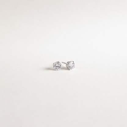 A pair of small silver stud earrings with clear gemstones, photographed on a plain white background.