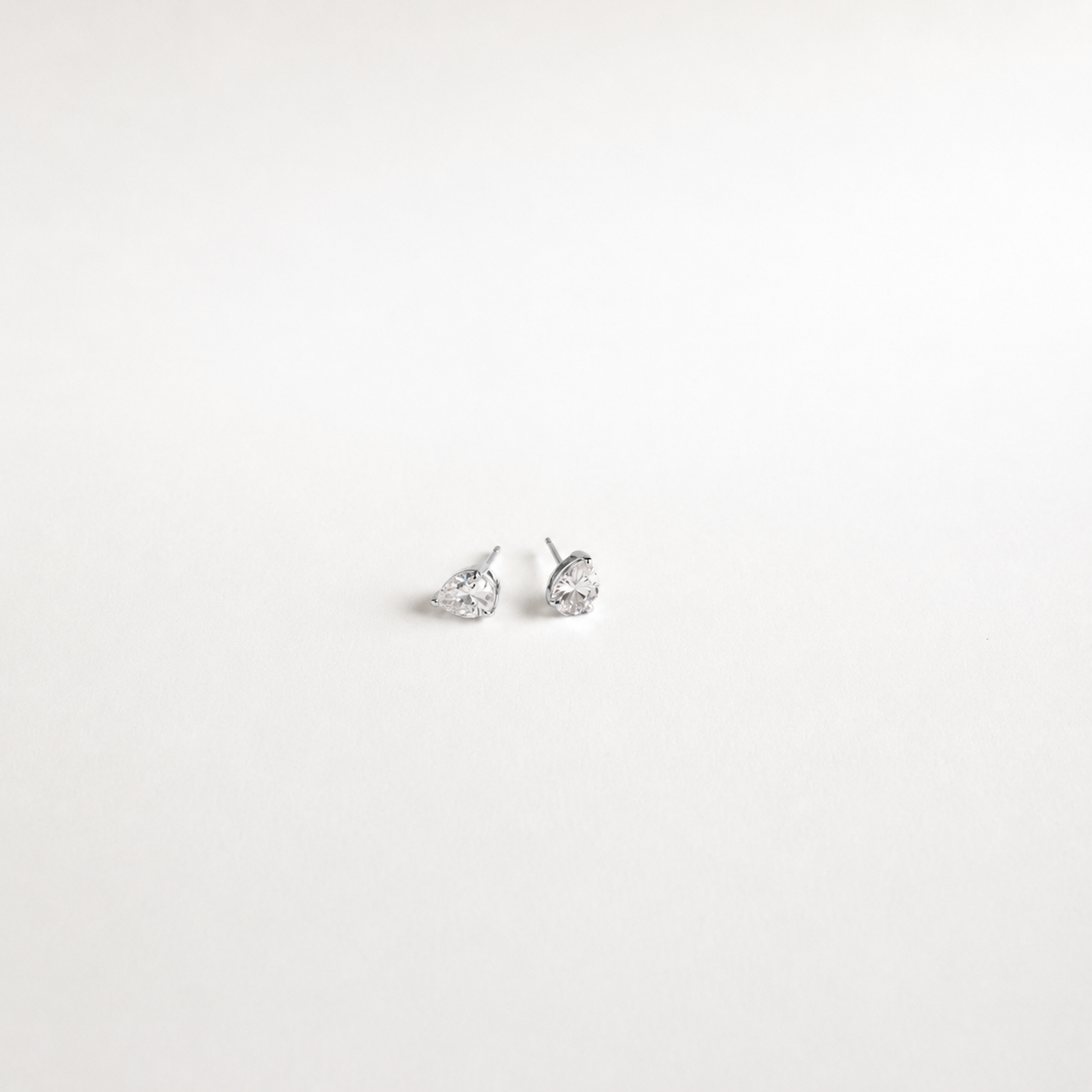 A pair of silver stud earrings with pear-cut clear gemstones, displayed on a clean white background.