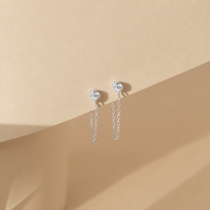 Silver chain earrings on a beige background
