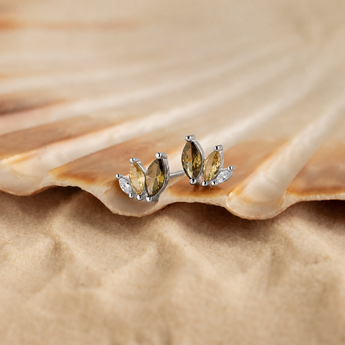 Pair of silver earrings with yellow gemstones on a seashell.