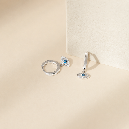Pair of silver earrings with gemstones on a beige background