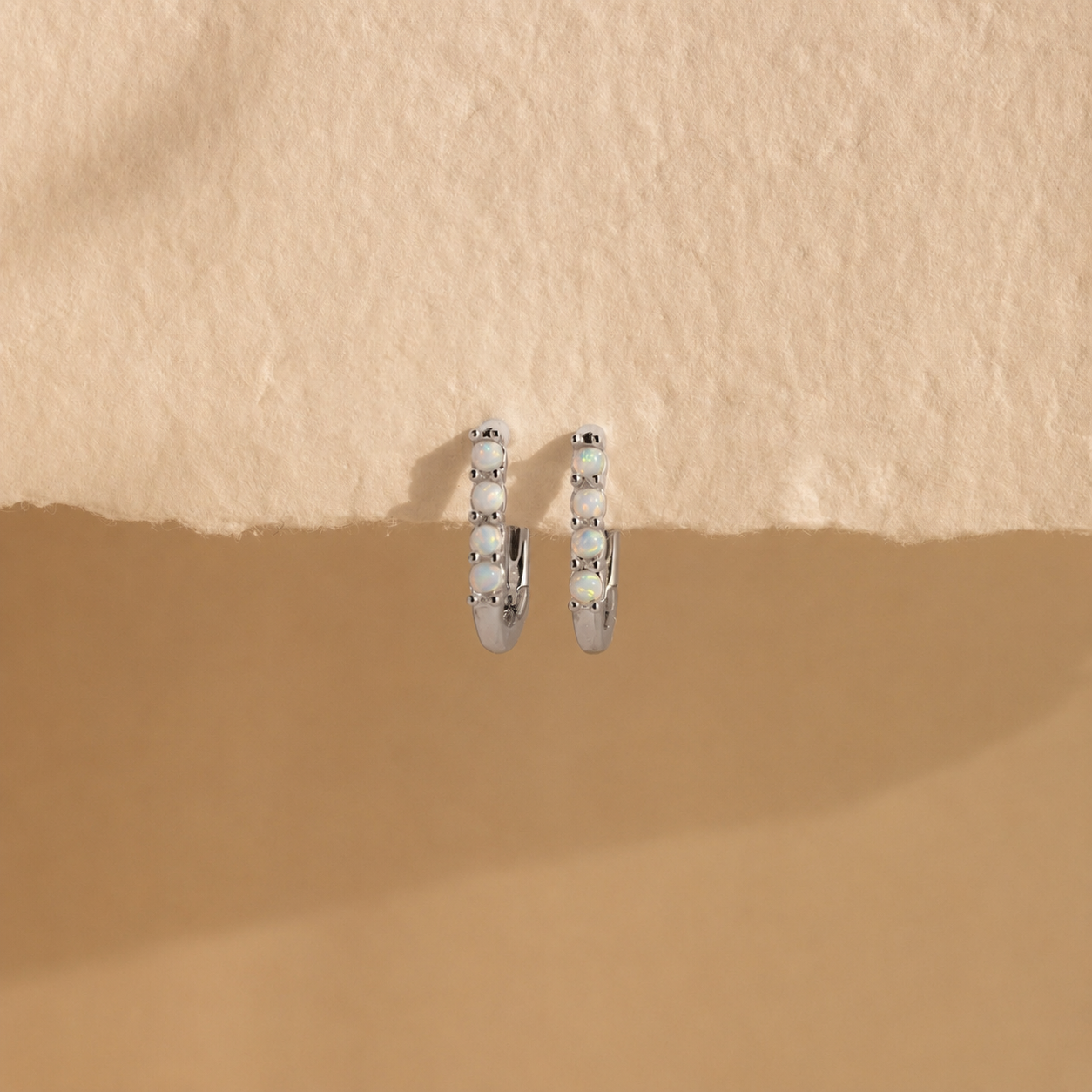 Silver hoop earrings on a beige background