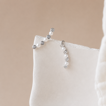Pearl and crystal earrings on a beige cushion with a neutral background