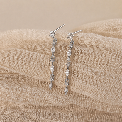 Silver earrings with clear stones on a beige fabric background