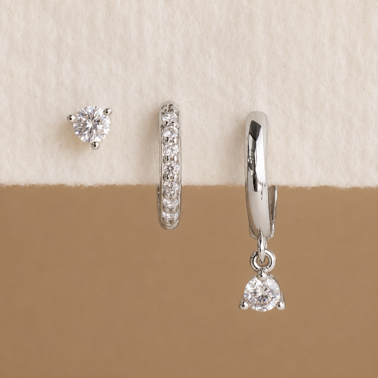 Set of silver earrings on a beige background