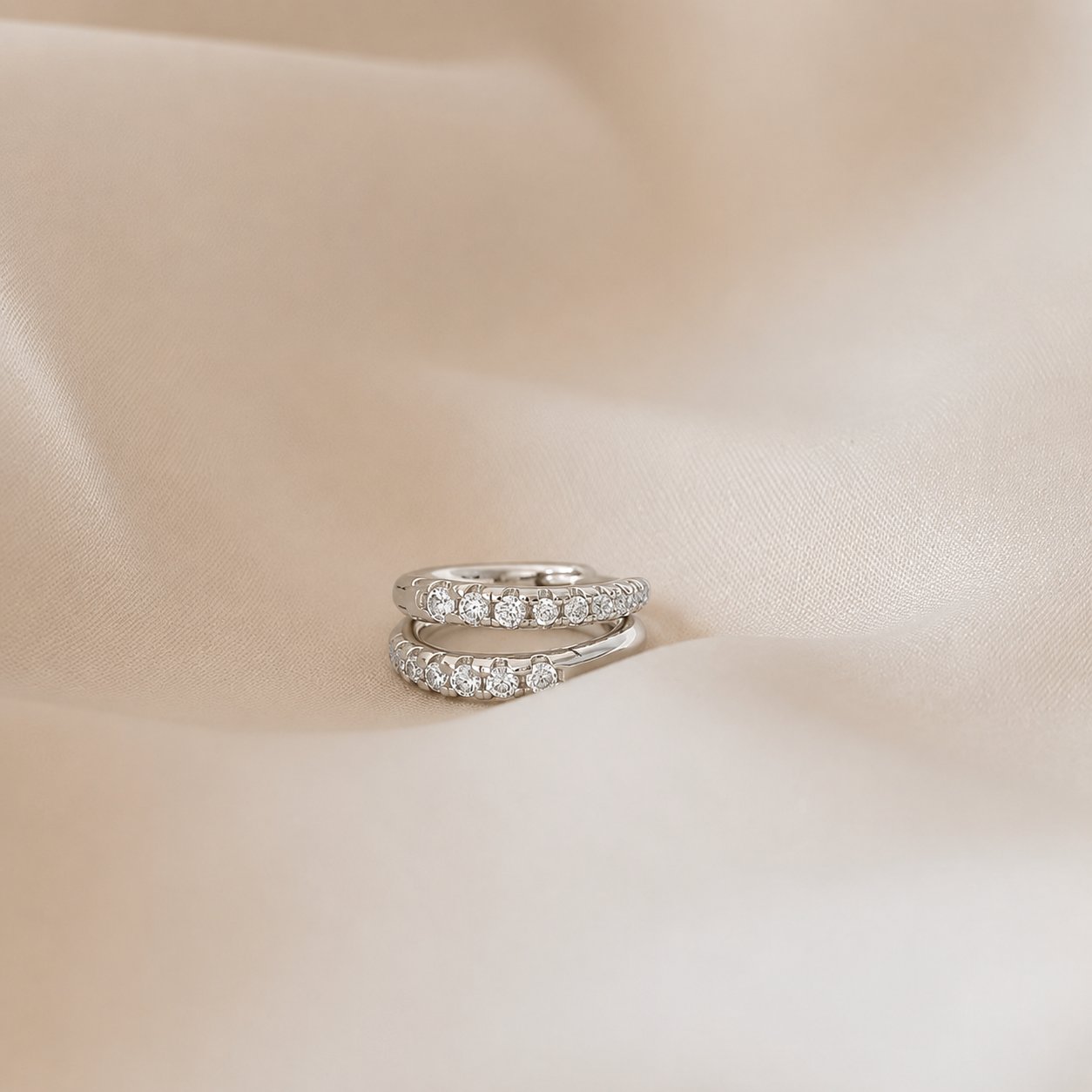 Two diamond rings on a soft beige fabric background