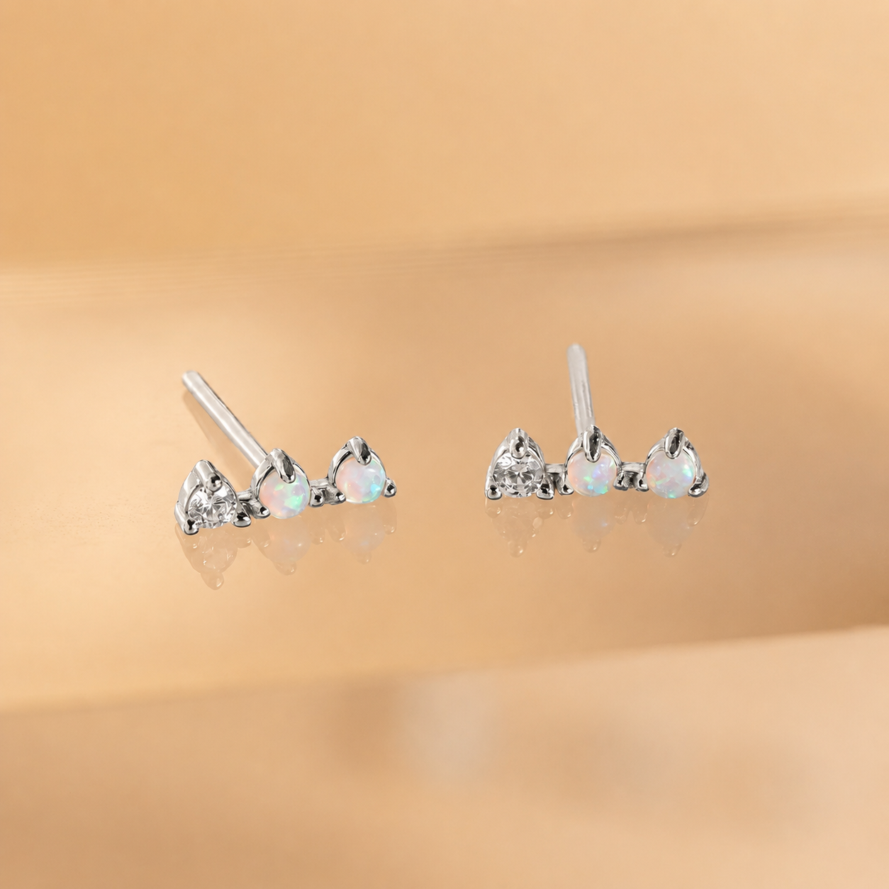 Pair of heart-shaped opal earrings on a beige background
