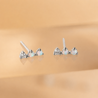 Pair of heart-shaped opal earrings on a beige background