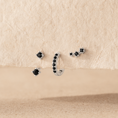 Set of black gemstone earrings on a beige surface