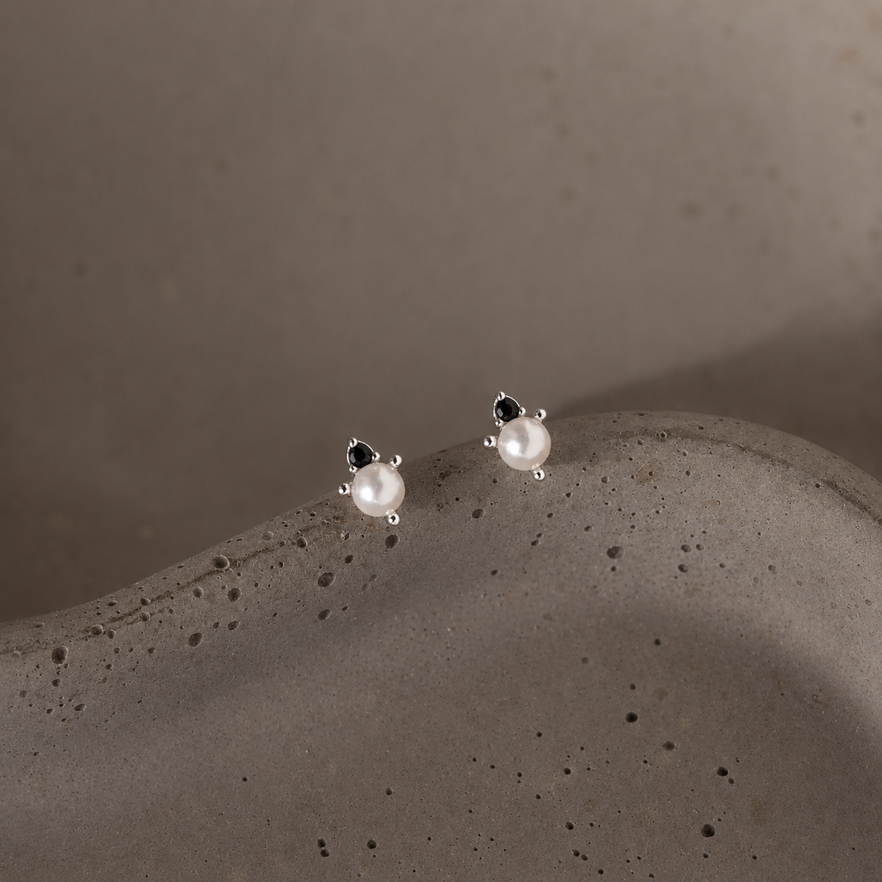 Pair of pearl earrings on a textured gray surface