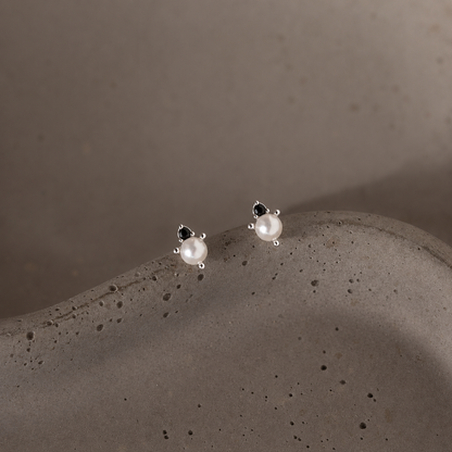 Pair of pearl earrings on a textured gray surface
