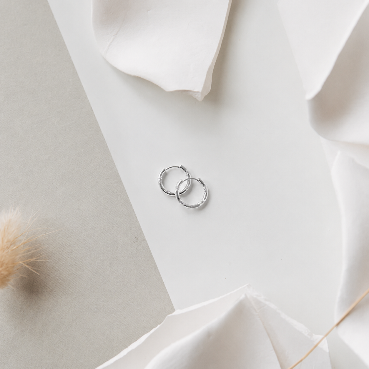 Two silver earring on a white fabric surface