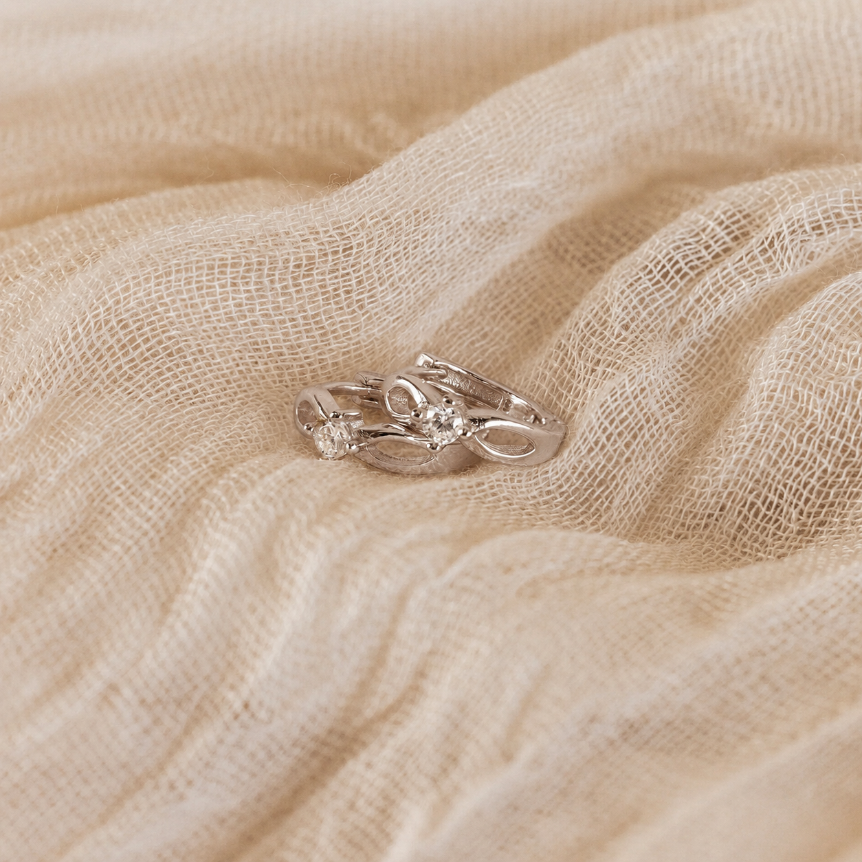 Silver ring with a diamond on a beige fabric background