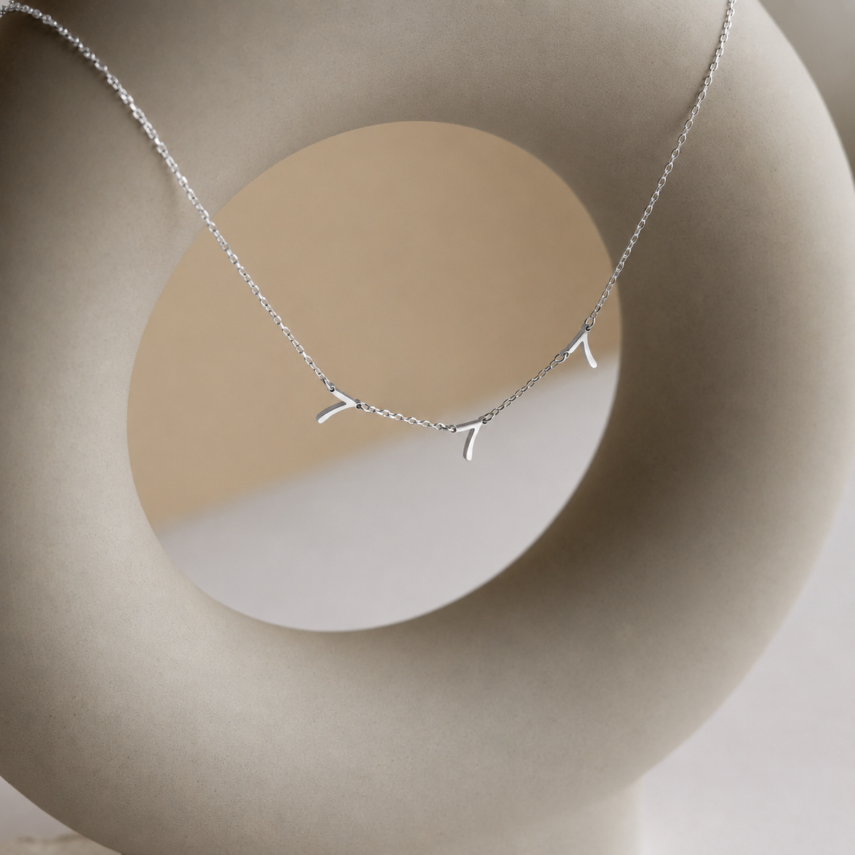 Silver necklace with a delicate branch design on a neutral background