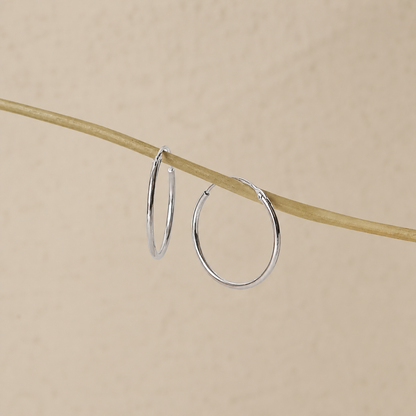 Silver hoop earrings on a beige background