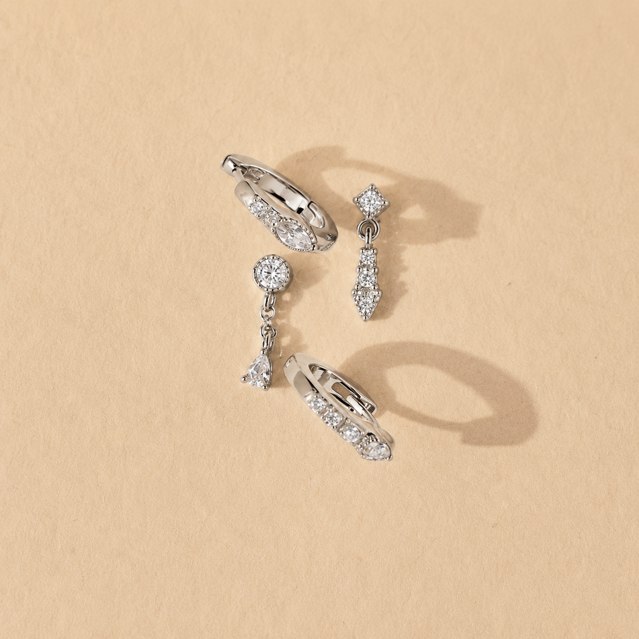 Set of silver earrings on a beige background