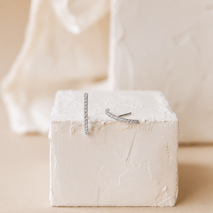 Silver necklace and ring on a textured white block with a soft beige background