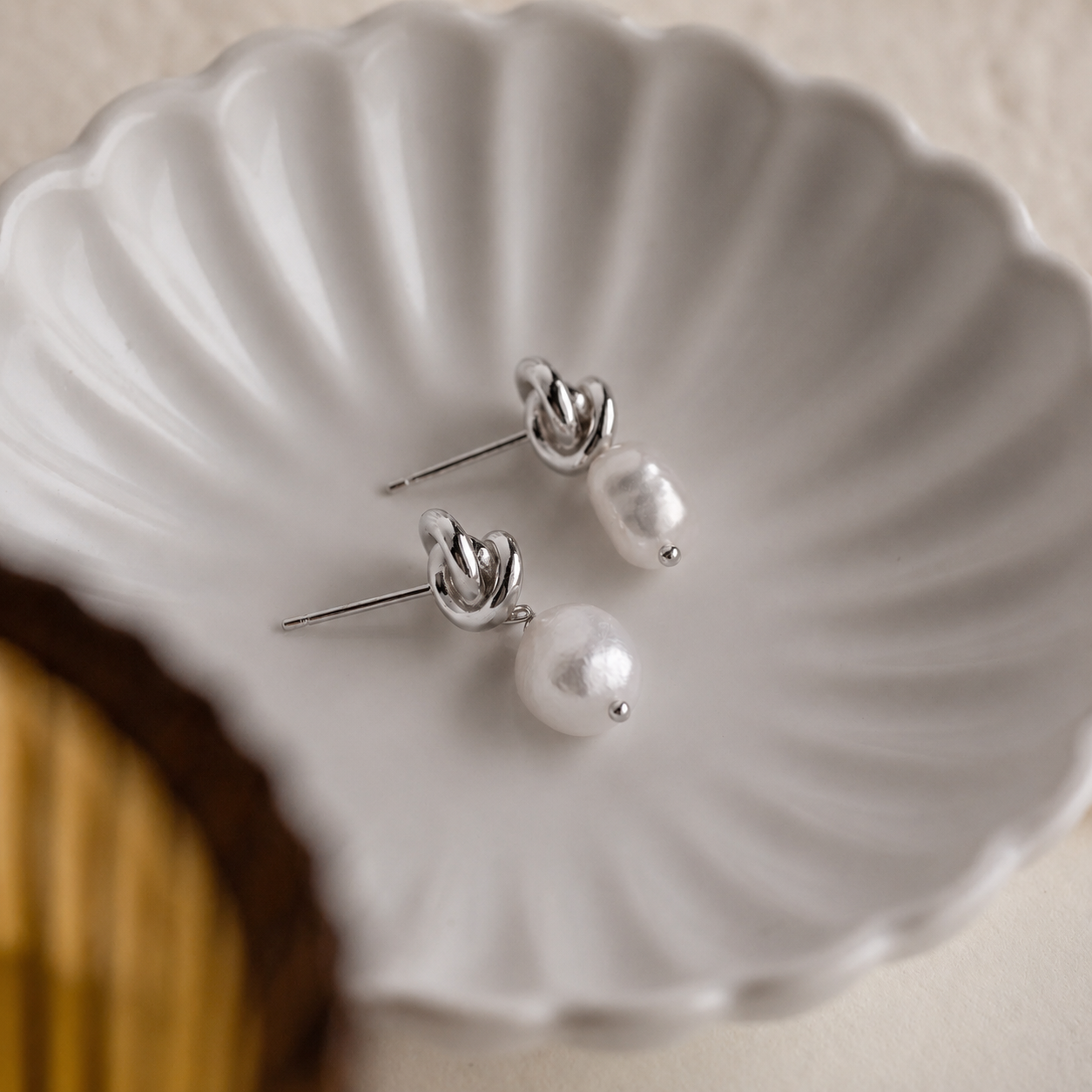 Pearl earrings on a white shell-shaped dish