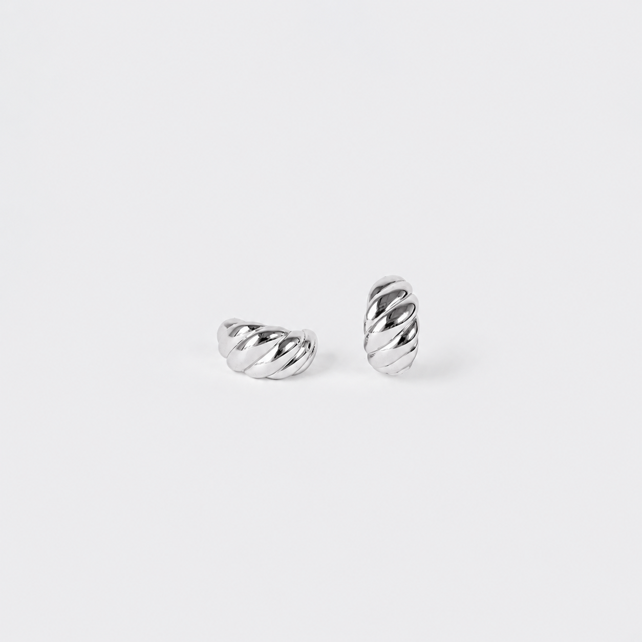 A pair of silver twisted cable hoop earrings on a clean, light gray background.