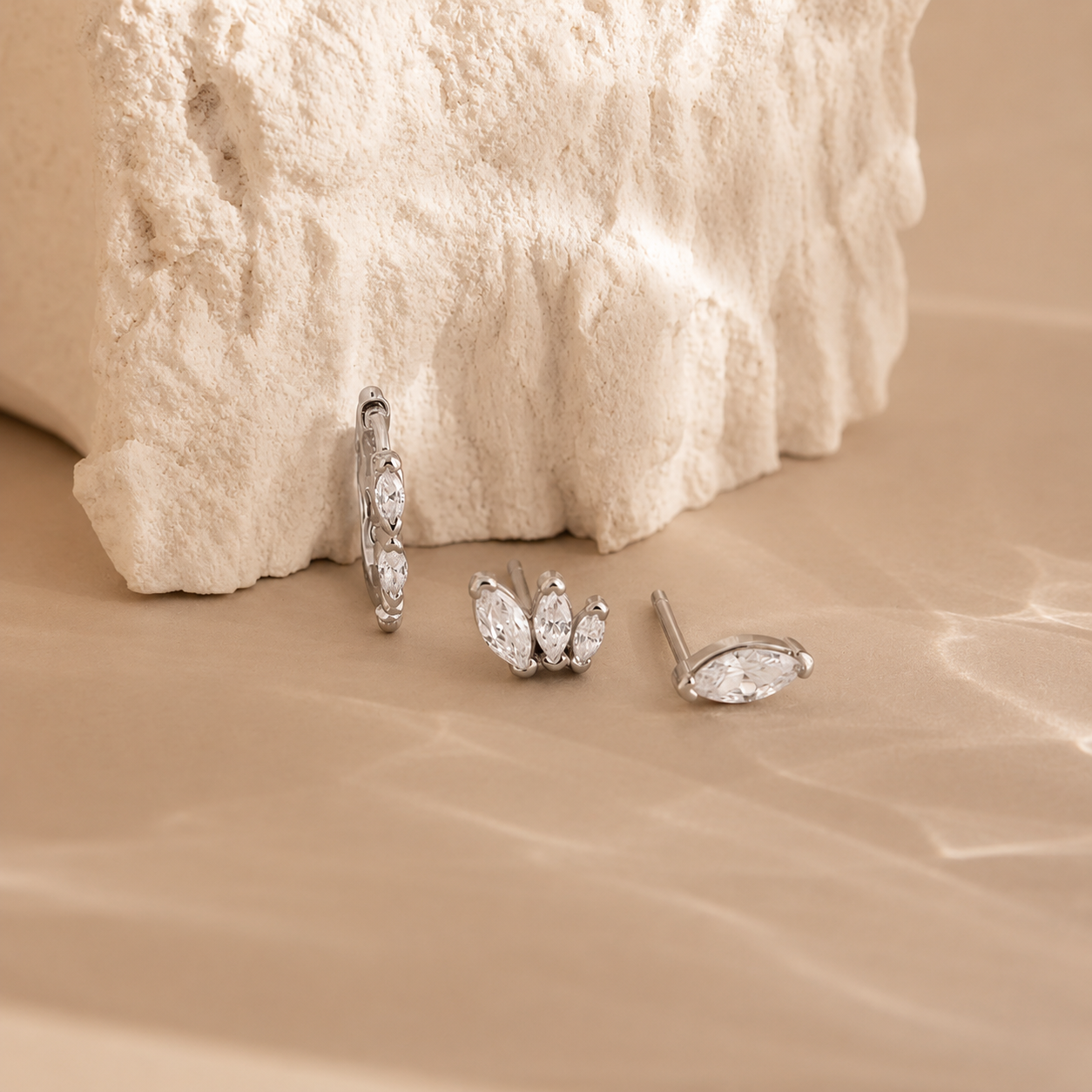 Set of silver earrings on a textured beige surface