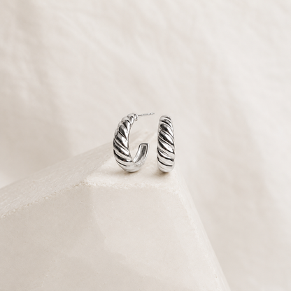 Silver hoop earrings on a light beige fabric background