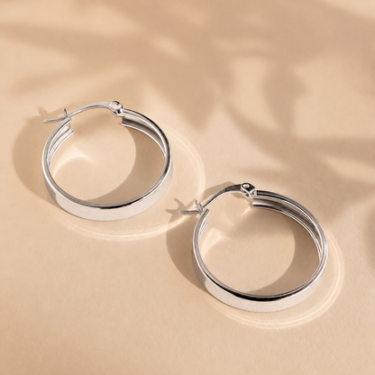 Pair of silver hoop earrings on a beige background