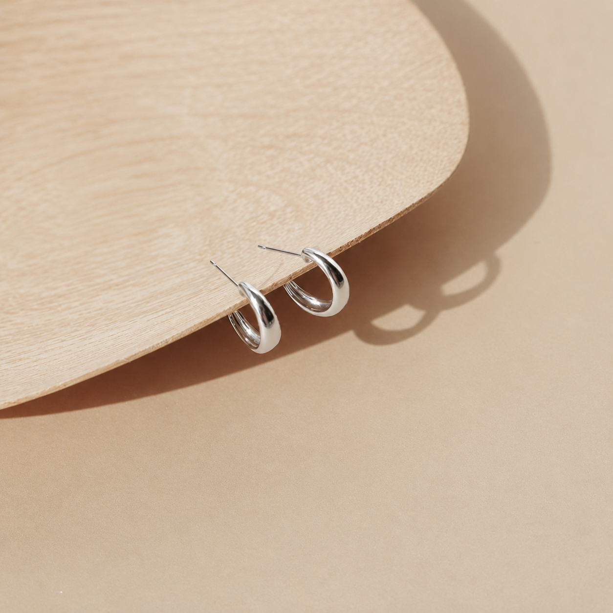 Silver hoop earrings on a beige surface