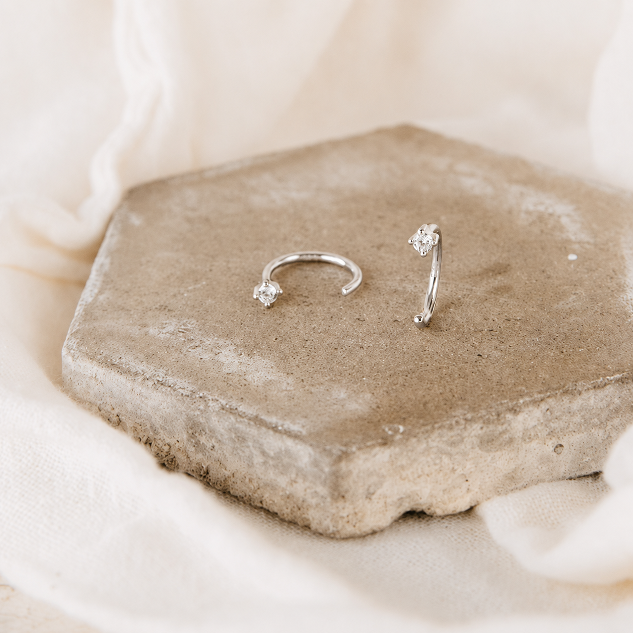 Silver nose ring with small gemstones on a stone surface