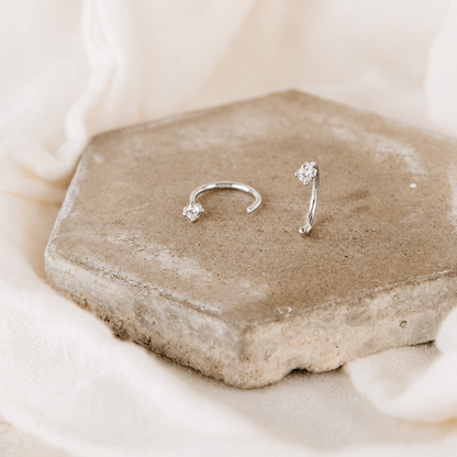 Silver nose ring with small gemstones on a stone surface