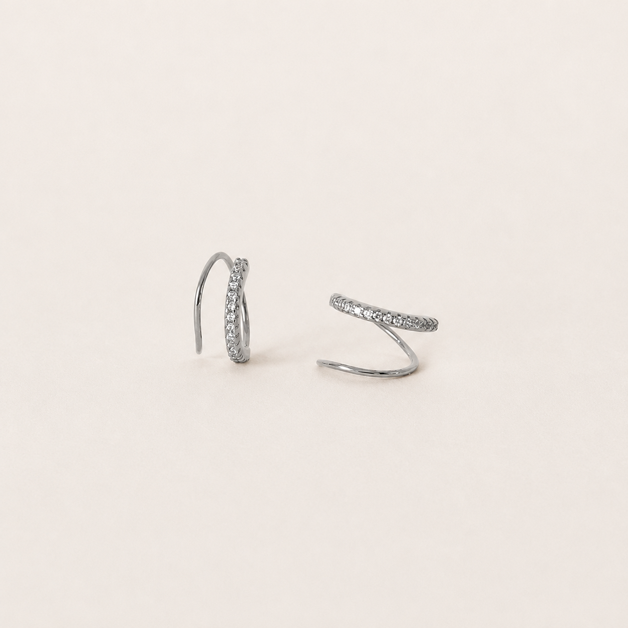 Pair of silver hoop earrings on a light beige background
