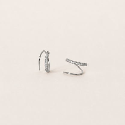 Pair of silver hoop earrings on a light beige background