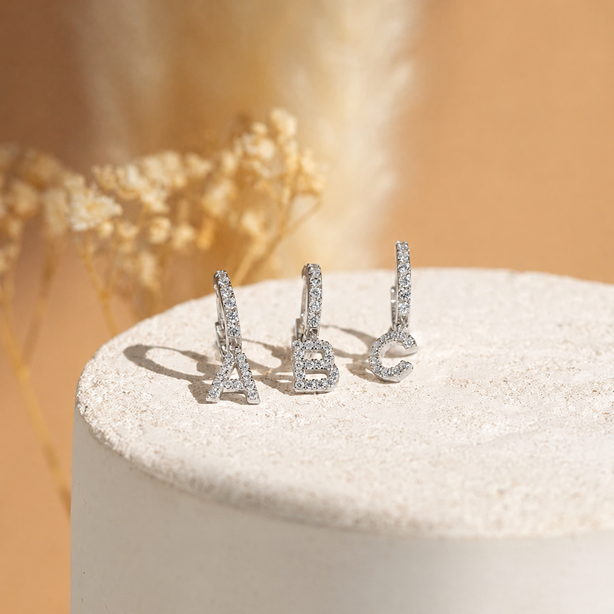 Silver earrings shaped like the Eiffel Tower on a white pedestal with a blurred floral background.