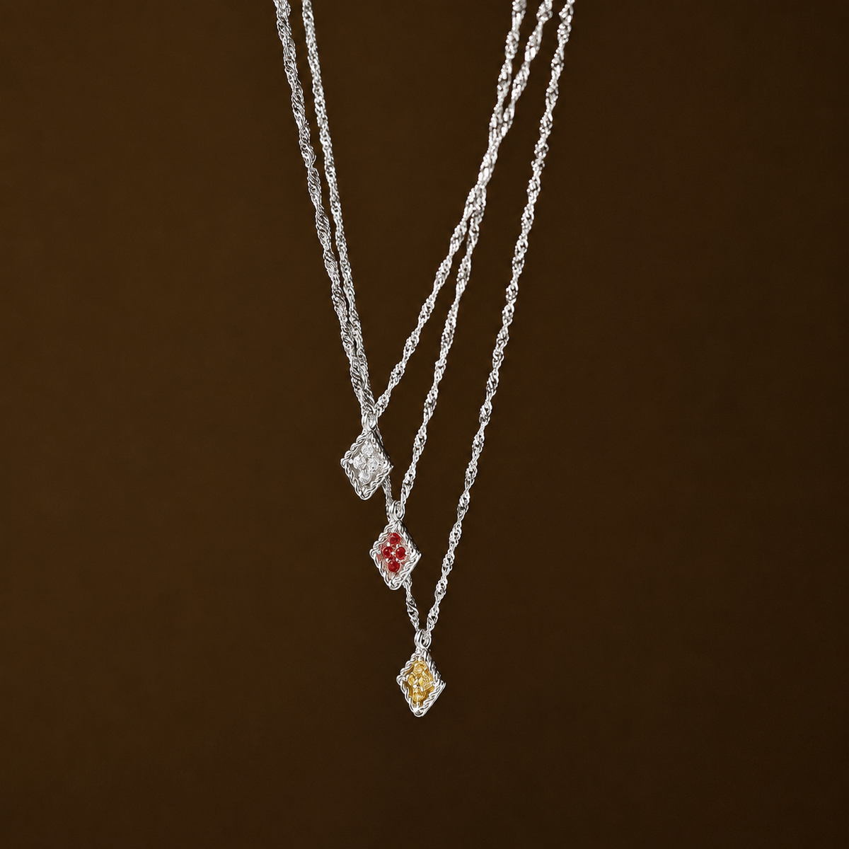 Silver necklace with three pendant drops on a brown background