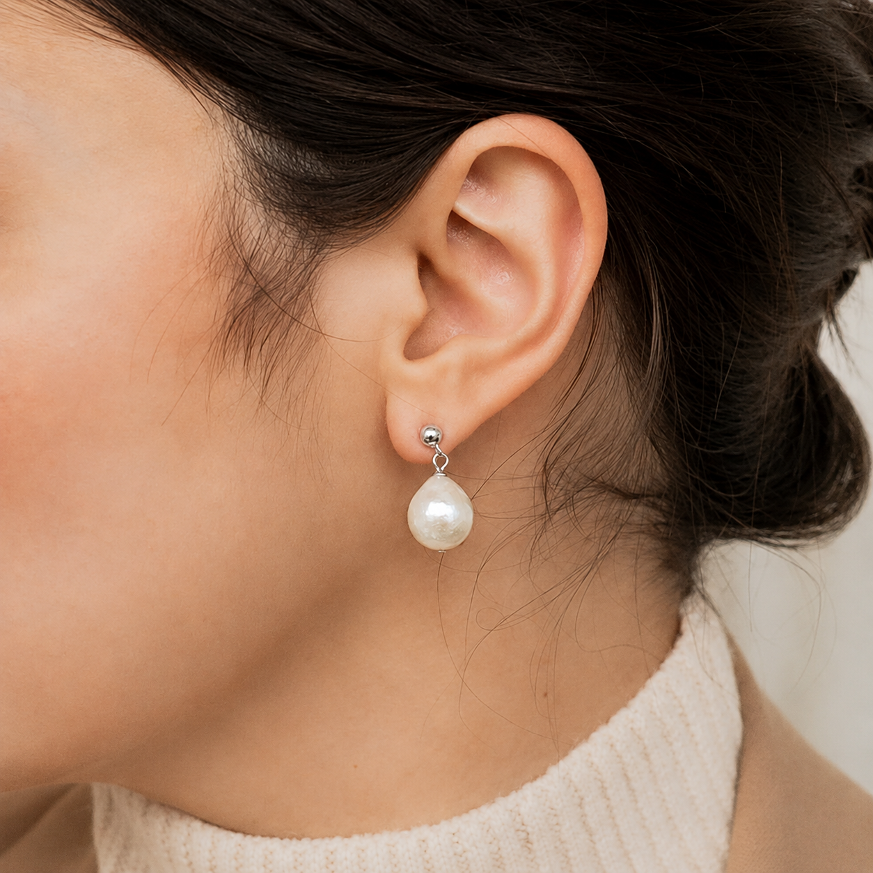 Pearl earring worn by a person with a neutral background