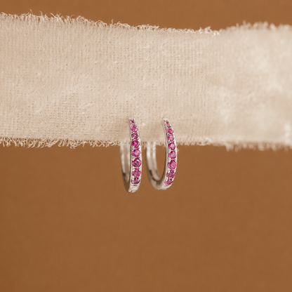 Pink hoop earrings on a beige fabric background