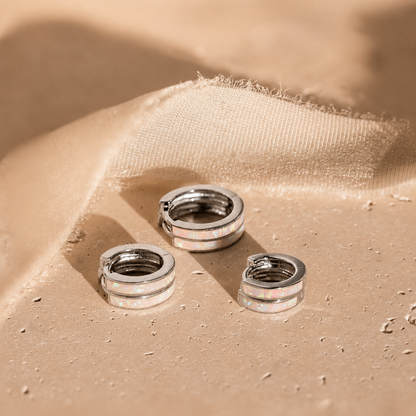 Three silver hoop earrings on a beige fabric surface