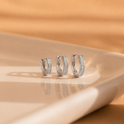 Set of silver hoop earrings on a beige surface