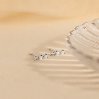 Silver earrings with gemstones on a beige fabric background