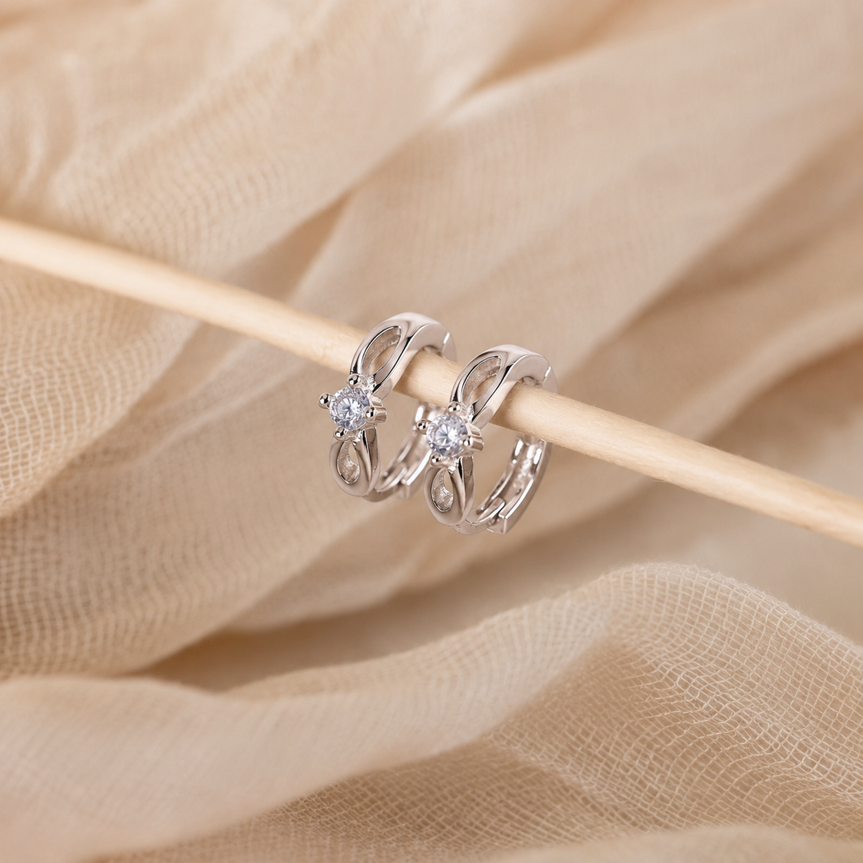 Silver rings with gemstones on a wooden stick against a beige fabric background