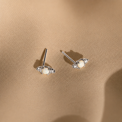 Pair of silver earrings with gemstones on a beige fabric background