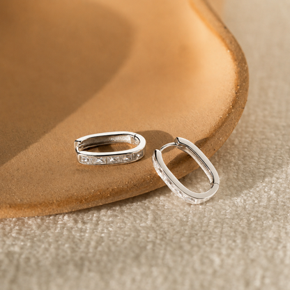 Silver hoop earrings on a textured beige surface